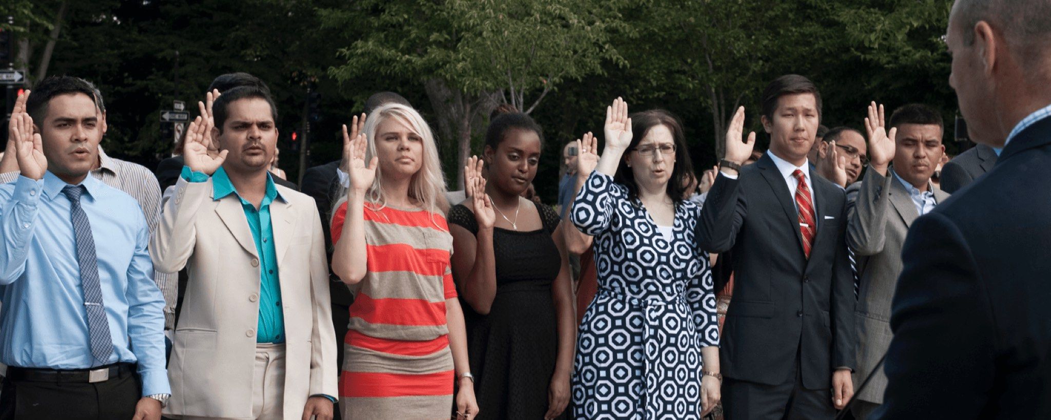 New citizens with their hands raised for the citizenship oath at a naturalization ceremony