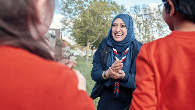 Scout leader in headscarf talking to young people
