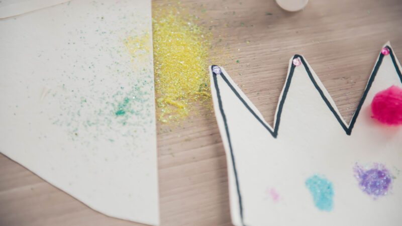 Royal related crafts on a table, including a handmade crown and glitter